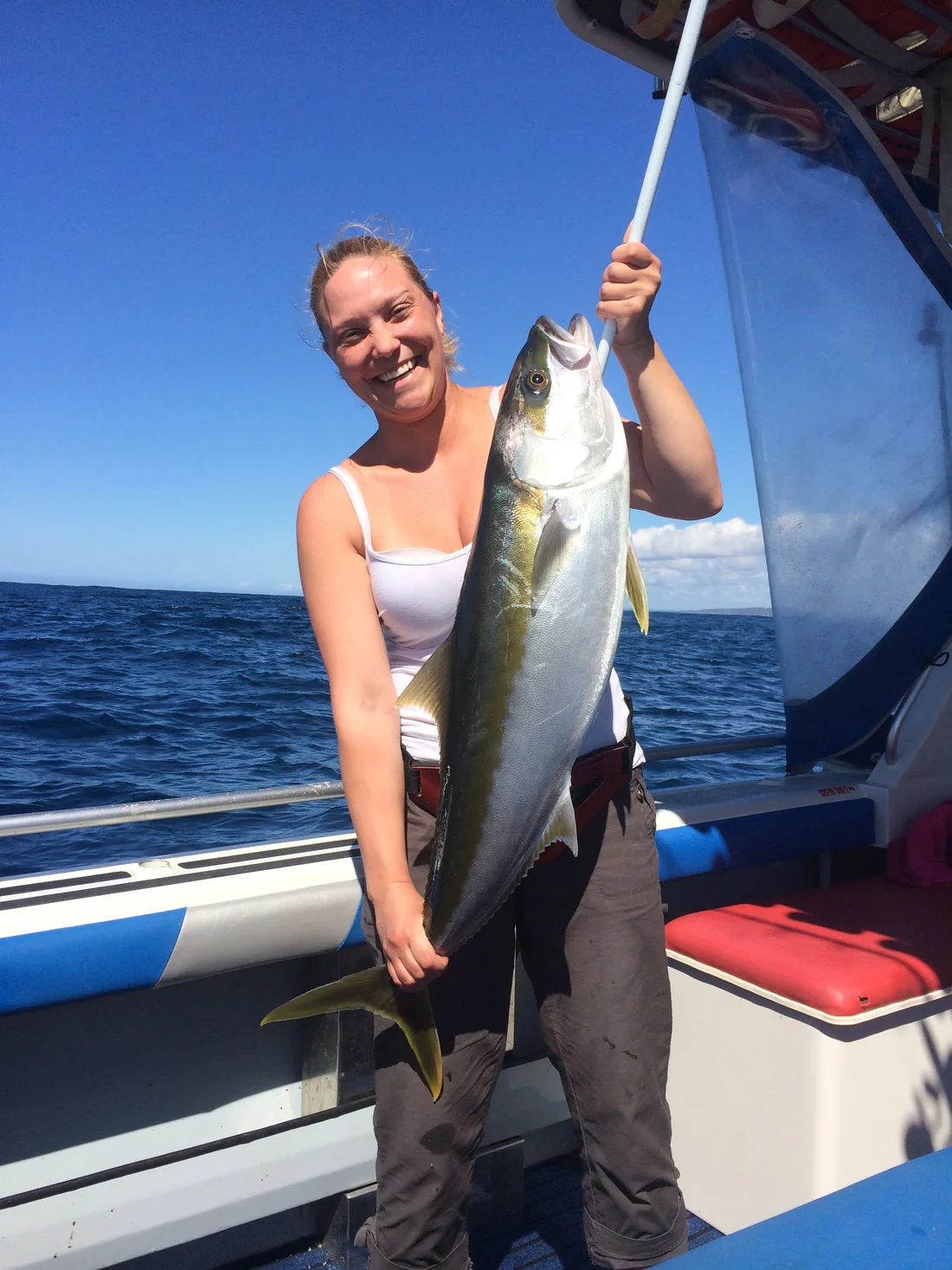 A guest holding a large kingfish on the deck of Windarra