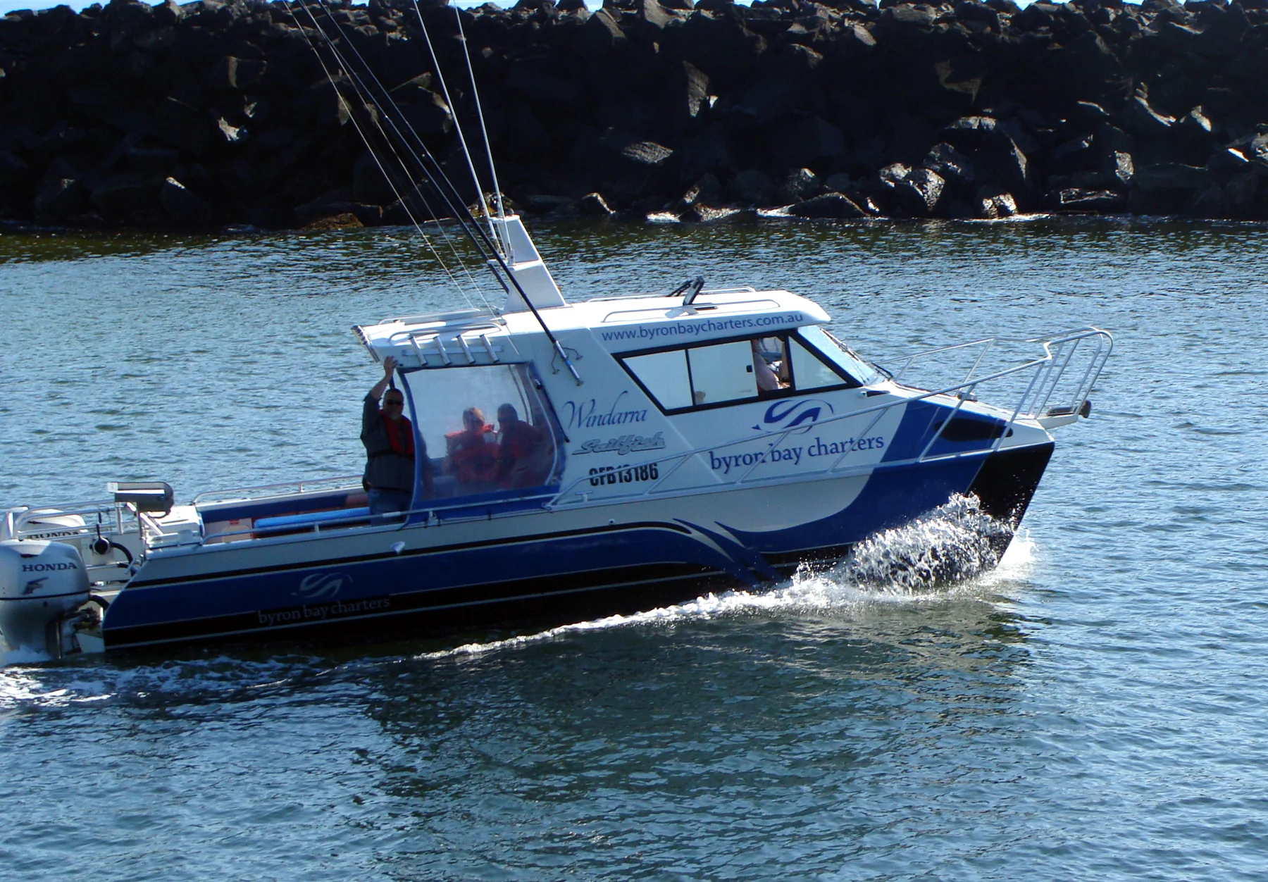 Windarra, a blue and white Sailfish catamaran, running out past the Brunswick Heads breakwall